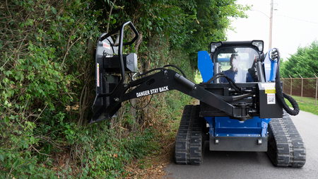 Blue Diamond swing arm brush cutter cutting vertically along overgrowth on a compact track loader