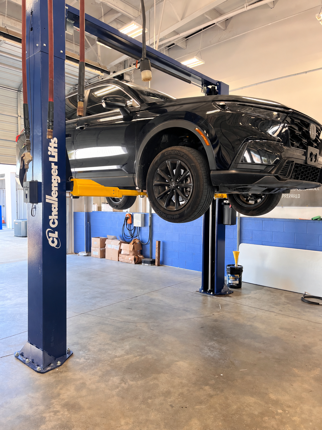 Black SUV raised on a Challenger vehicle lift in a professional service bay